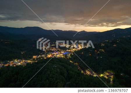 Gatlinburg, Tennessee at night with illuminated Parkway street lined with restaurants, attractions and retail shops for visitors. Forested Appalachian hills surrounding American vacation town. 136979707