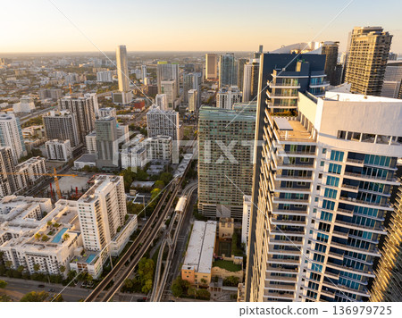 Aerial scene of Miami Brickell elevated railroad and passing commuter train between tall buildings and glowing sunset in Florida, USA 136979725