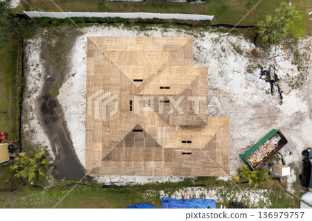 Asphalt shingle roofing in progress. Construction covering new house rooftop. Residential development in the USA. 136979757
