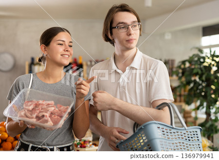 European youth girl and guy choose raw pork chop tenderloin for roasting in store European youth girl and guy choose raw pork chop tenderloin for roasting in store 136979941