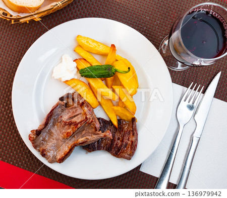 on large white plate heaps of fried beef seasoned with green pepper with fried potatoes and sauce on large white plate heaps of fried beef seasoned with green pepper with fried potatoes and sauce 136979942