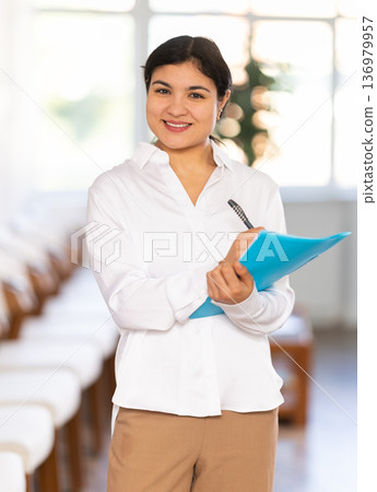 Portrait of friendly female receptionist with folder Portrait of friendly female receptionist with folder 136979957