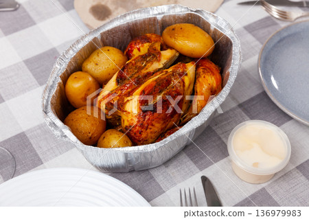 Fried chicken with baked potatoes served in foil Fried chicken with baked potatoes served in foil 136979983