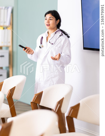 Woman doctor with remote control in lecture hall 136979991