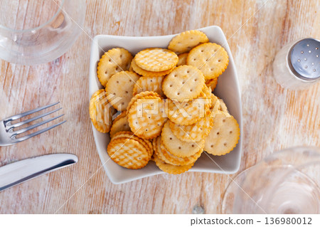 Crispy disc-shaped lightly salted crackers in plate on table Crispy disc-shaped lightly salted crackers in plate on table 136980012