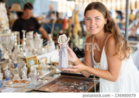 Female traveler buyer chooses ceramic antiquarian porcelain shepherdess 136980079