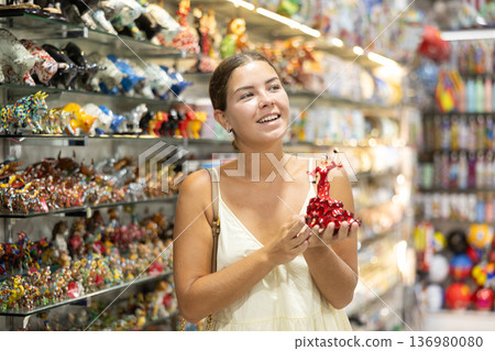 Female tourist chooses figurine of spanish dancer in souvenir shop 136980080