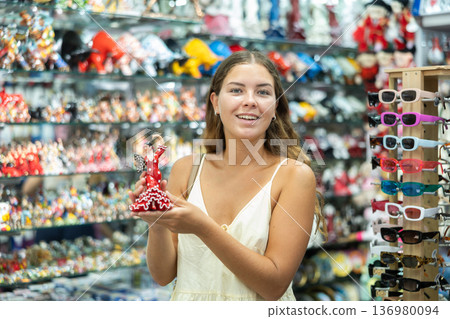 Female buyer holds in hands tests figurine she-dancer flamenco in memorable gifts shop Female buyer holds in hands tests figurine she-dancer flamenco in memorable gifts shop 136980094