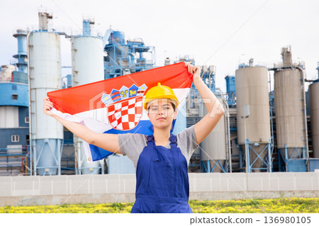 Worried girl in work clothes and hardhat with flag of croatia standing in front of industrial scenery 136980105