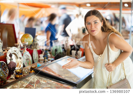 Interested young woman choosing interesting antique things at traditional flea market Interested young woman choosing interesting antique things at traditional flea market 136980107