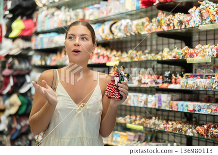 Happy young woman choosing statue of Spanish dancer among various souvenirs in gift shop in Barcelona Happy young woman choosing statue of Spanish dancer among various souvenirs in gift shop in Barcelona 136980113