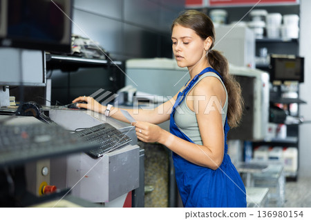 Young woman worker operating computerised machine to mix paint in paint shop Young woman worker operating computerised machine to mix paint in paint shop 136980154