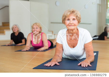 Senior women practicing cobra pose Senior women practicing cobra pose 136980279