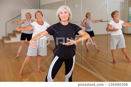 Aged woman practicing ballet dance moves in choreographic studio Aged woman practicing ballet dance moves in choreographic studio 136980306
