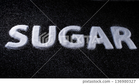 Sugar written in granulated form on a black surface showcasing a creative food art display Sugar written in granulated form on a black surface showcasing a creative food art display 136980327