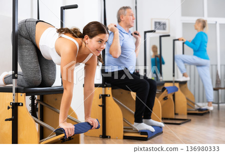 Young European woman making Pilates exercising while standing on knees using Wanda chair machine at gym 136980333