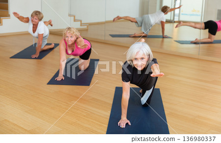 Mature active women perform a stretching exercise Mature active women perform a stretching exercise 136980337