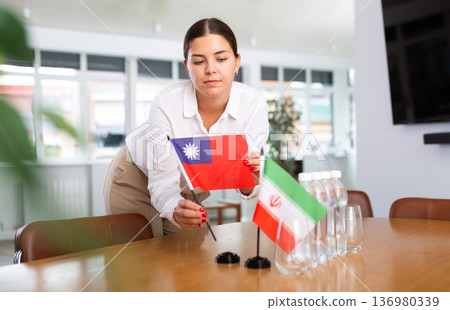Positive young woman putting little flag of Taiwan on table next to the flag of Iran Positive young woman putting little flag of Taiwan on table next to the flag of Iran 136980339