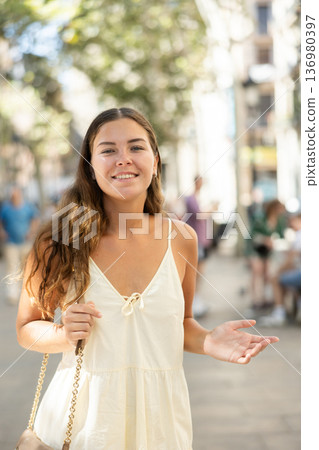 Happy young girl in dress walking in summer city 136980397