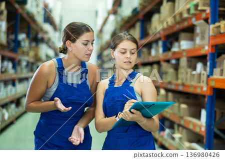 Two girls check papers invoices and revise availability of goods in paint and varnish stock Two girls check papers invoices and revise availability of goods in paint and varnish stock 136980426