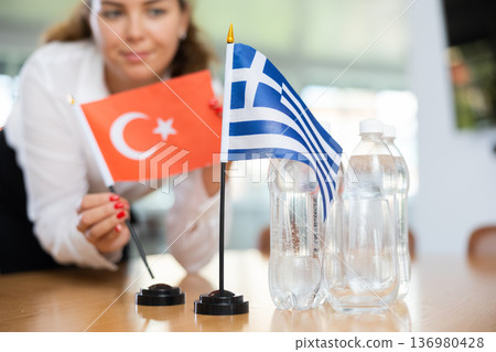 Unrecognizable girl sets midget flags of Greece and Turkey before international negotiations 136980428