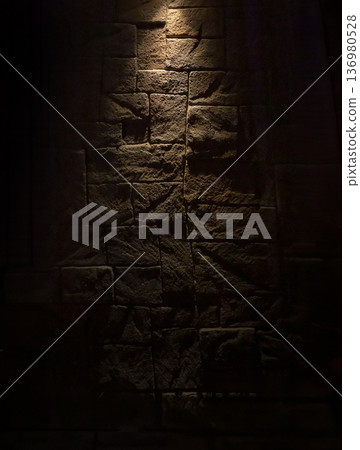 Dramatic stone wall texture with spotlight and shadows. Dark moody background of ancient masonry for interior design, mystery, or architectural concept Dramatic stone wall texture with spotlight and shadows. Dark moody background of ancient masonry for interior design, mystery, or architectural concept 136980528