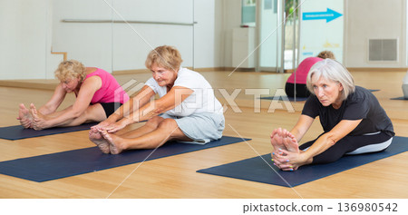 Mature women perform an exercise of intensive stretching of the back surface of the body Paschimottanasana Mature women perform an exercise of intensive stretching of the back surface of the body Paschimottanasana 136980542
