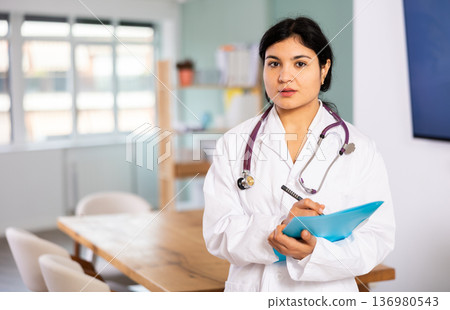 Doctor woman with document stands in office space Doctor woman with document stands in office space 136980543
