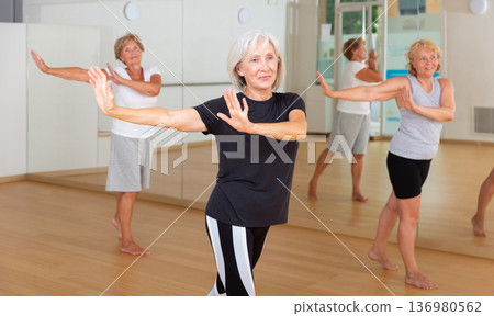 Mature women performing dance in exercise room 136980562