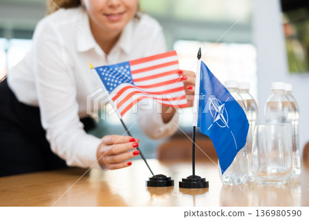 Young female secretary preparing room for international negotiations between nato and usa Young female secretary preparing room for international negotiations between nato and usa 136980590