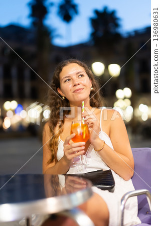 On summer outside of cafe, girl is relaxing at table, drinking chilled coctail. 136980631