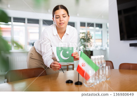 Positive young woman putting little flag of Pakistan on table next to the flag of Iran 136980649