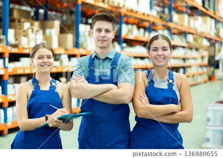 Young female and male employees of store goods for repair and construction are standing in warehouse Young female and male employees of store goods for repair and construction are standing in warehouse 136980655