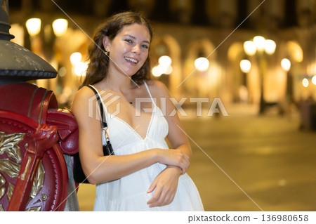 Young smiling woman at Royal square, leaning on Gaudis lantern, spend time in public urban space 136980658