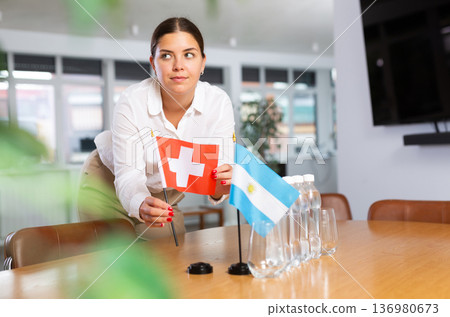 Young lady sets miniatures flags of Argentina and Switzerland for international negotiations Young lady sets miniatures flags of Argentina and Switzerland for international negotiations 136980673