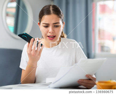 Outraged woman with documents in her hands talking on mobile phone 136980675