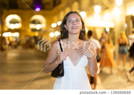 young woman walks along an evening street in Barcelona young woman walks along an evening street in Barcelona 136980680