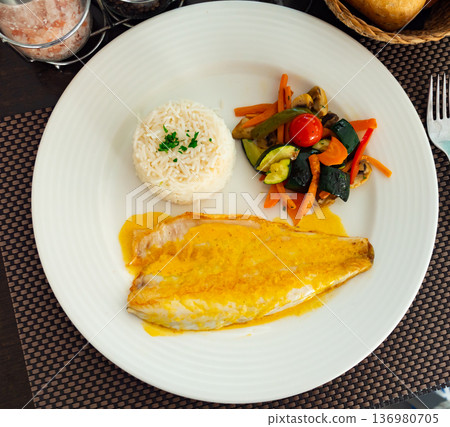 Sea bass fillet with curry sauce and basmati rice 136980705