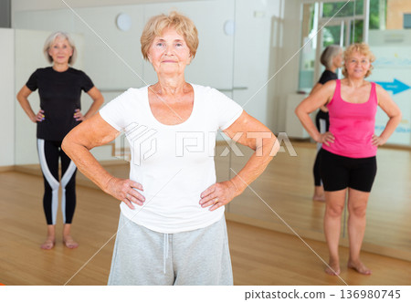 Senior woman stretching between asanas during group yoga training Senior woman stretching between asanas during group yoga training 136980745