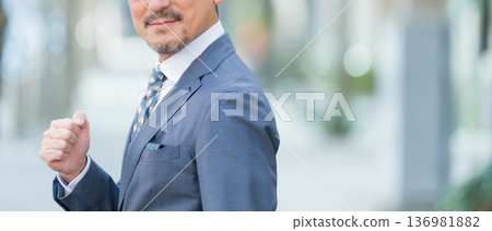 Businessman pumping his fist outdoors 136981882