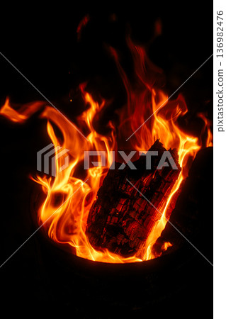 A vibrant flame flickers in the darkness. An image of a passionate fire reminiscent of campfires and outdoor activities. 136982476