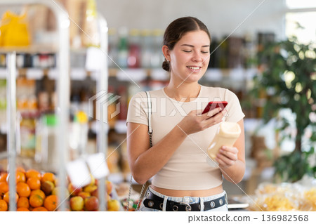 Young woman scanning qr code for mayonnaise Young woman scanning qr code for mayonnaise 136982568
