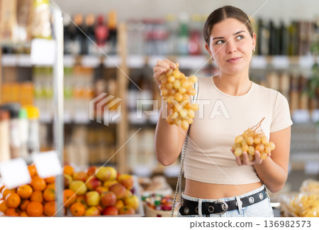 Young woman choosing grapes in grocery store Young woman choosing grapes in grocery store 136982573