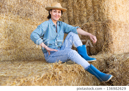 Asian woman farmer resting on hayloft 136982629