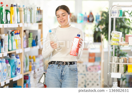 Girl housewife in household store examines goods, chooses sewer cleaner liquid 136982631
