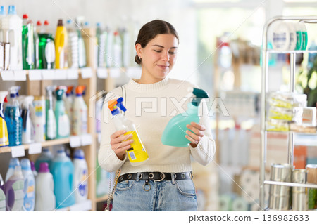 Woman choosing a cleaning spray Woman choosing a cleaning spray 136982633