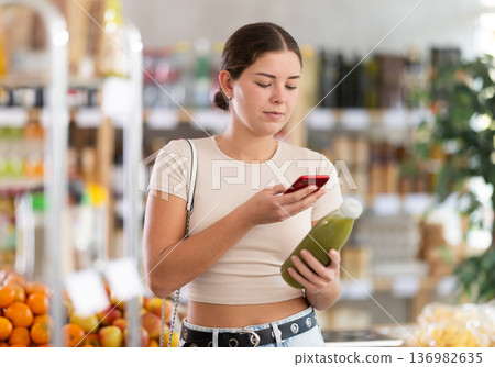Young woman scanning qr code for green smoothie 136982635