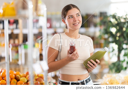 Young woman chooses red and green smoothie Young woman chooses red and green smoothie 136982644