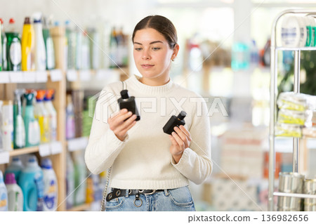 Young woman client sniffs fragrance of perfume, chooses scent spray with pleasant smell Young woman client sniffs fragrance of perfume, chooses scent spray with pleasant smell 136982656