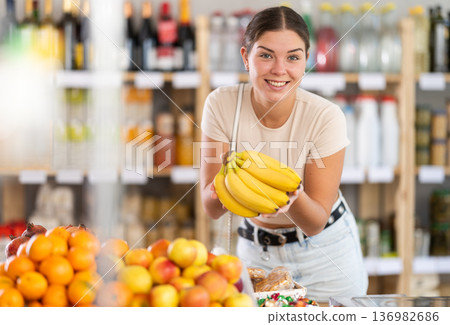 Young woman choosing bananas at grocery store 136982686